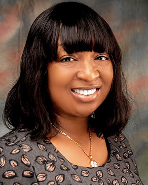 Young woman wearing a brown shirt with a leaf pattern and a gold necklace.